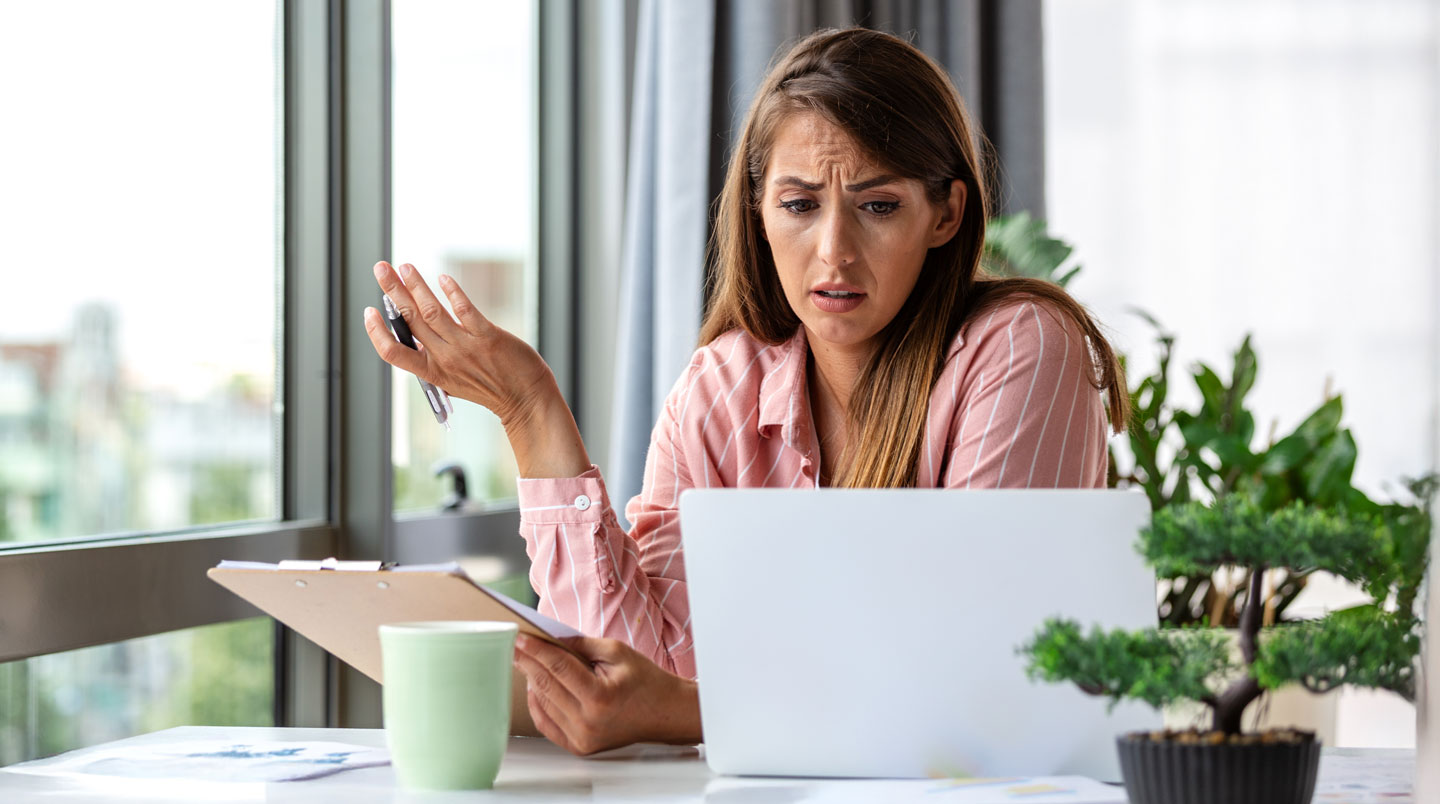 Employé du service client comparant des fiches produits imprimées présentant des informations contradictoires dans un bureau moderne